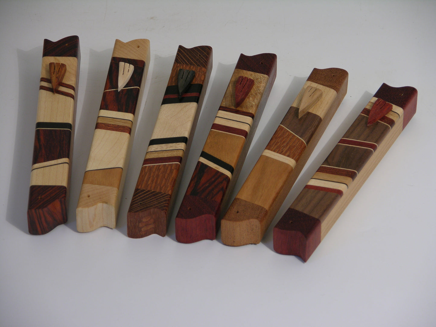 EC3A mezuzah case in mixed hardwoods with carved wooden shin; approx. 4.75 inches long.
