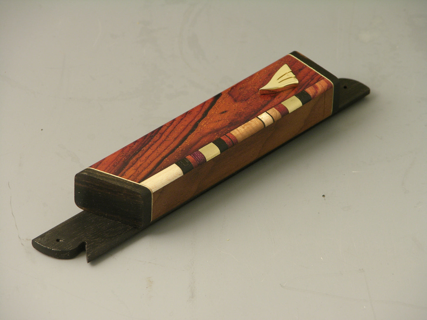 EC7 mezuzah case with cocobolo body, ebony accents, and gold-plated shin; side inlay of hardwoods and brass.
